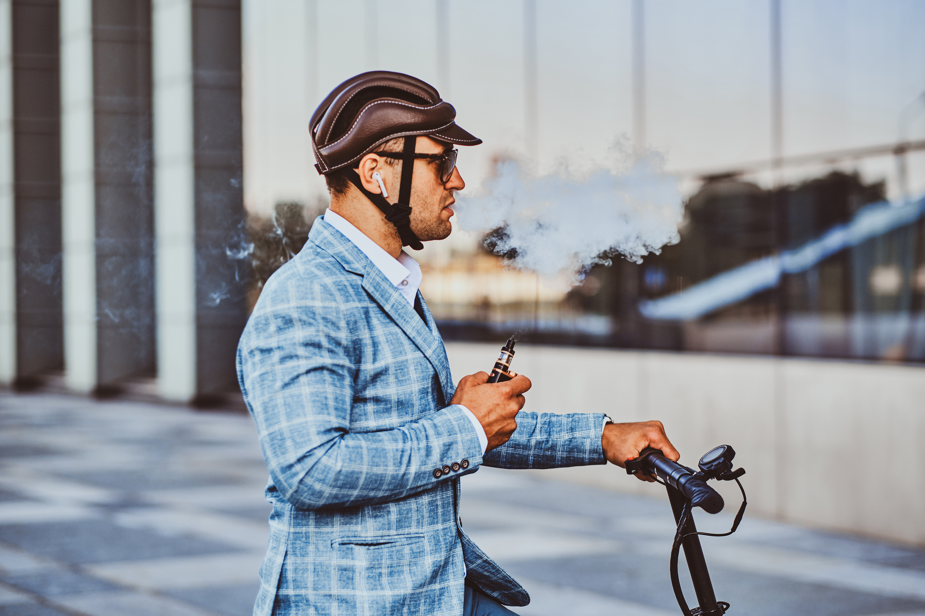 Elegant man with electro scooter is smoking vape